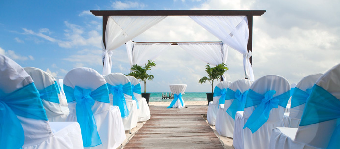 Cérémonie sur la plage à l'île Maurice : chaises blanches à nœuds turquoise et arche de mariage