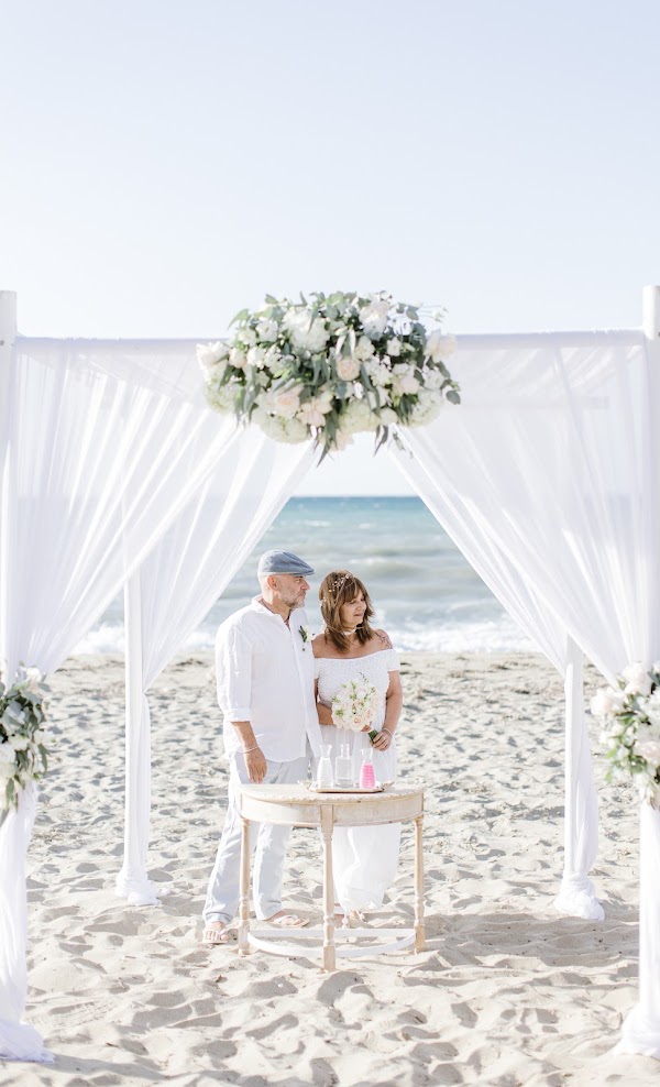 Chantal et Fabrice, mariés sous une arche drapée de blanc sur la plage