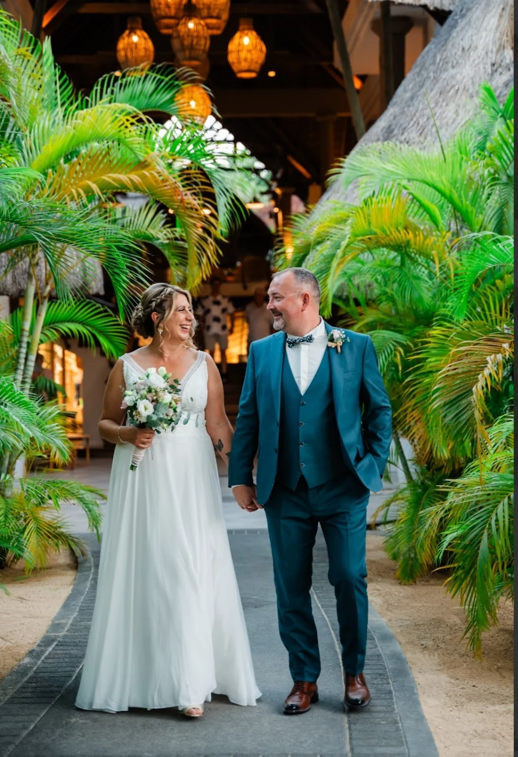 Nathalie et Yonni, mariés à l'île Maurice, marchant main dans la main dans les jardins de l'hôtel