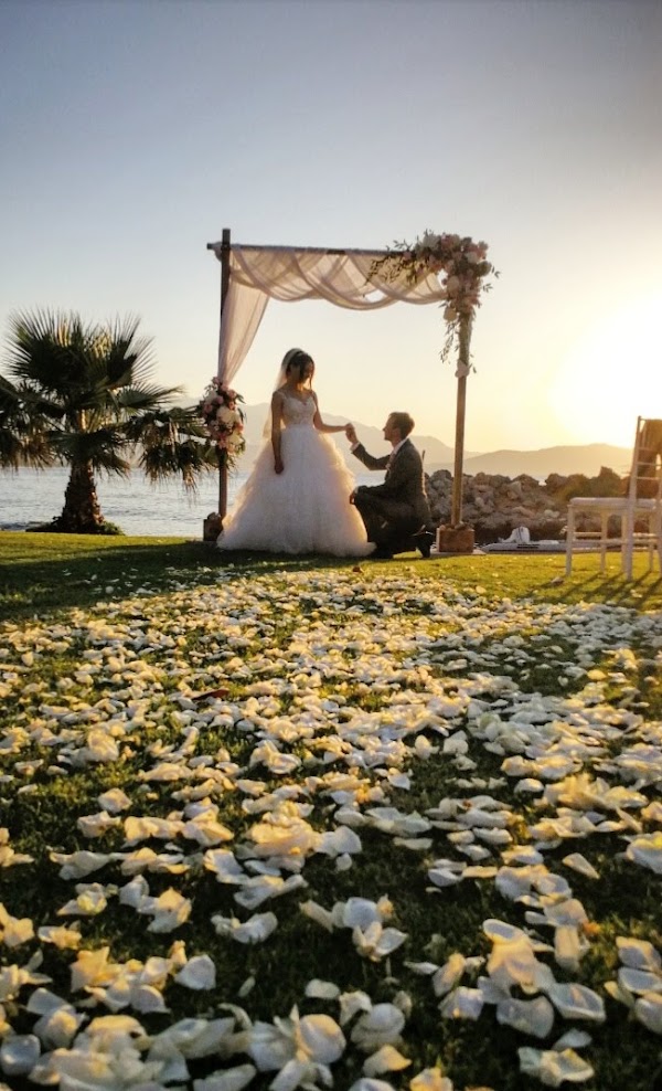 Sally et Jérémy, mariés en Crète, devant l'arche, sur un tapis de pétales au coucher du soleil
