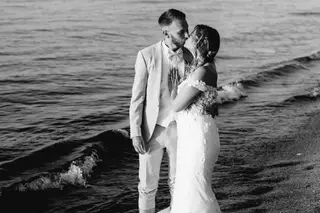 Sophie et Clément, mariés en Crète, qui s'embrassent dans les vagues (photo en noir et blanc)