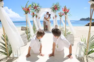 Stéphanie et Fabrice, mariés aux Seychelles, au bout de l'allée de la plage où leurs deux garçons s'agenouillent