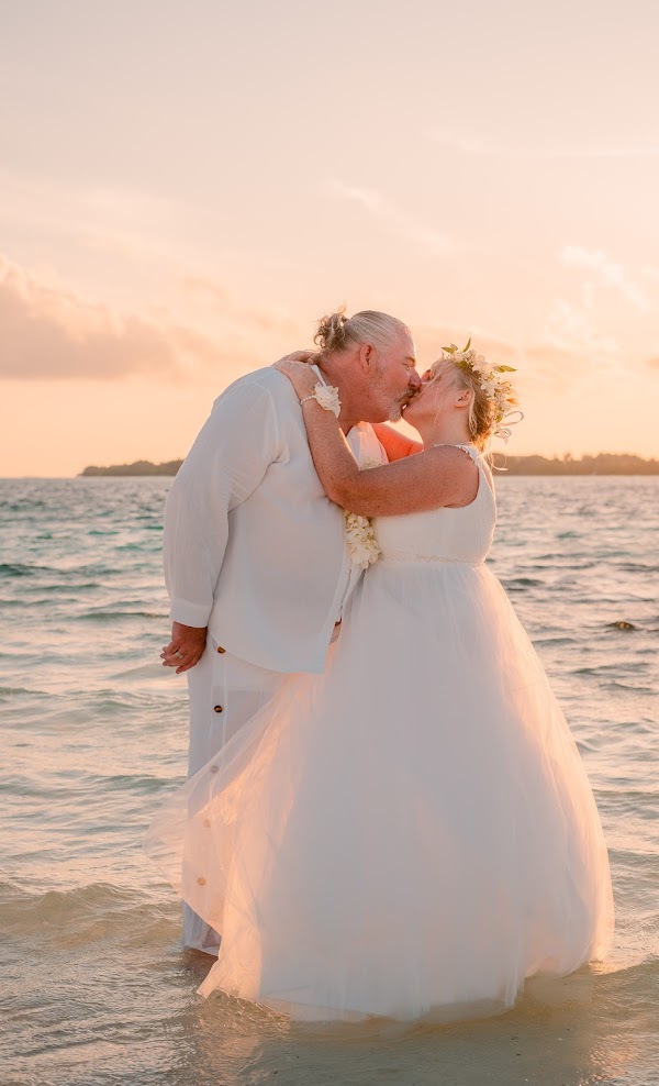 Valérie et Philippe, mariés aux Maldives, enlacés dans la mer au coucher du soleil